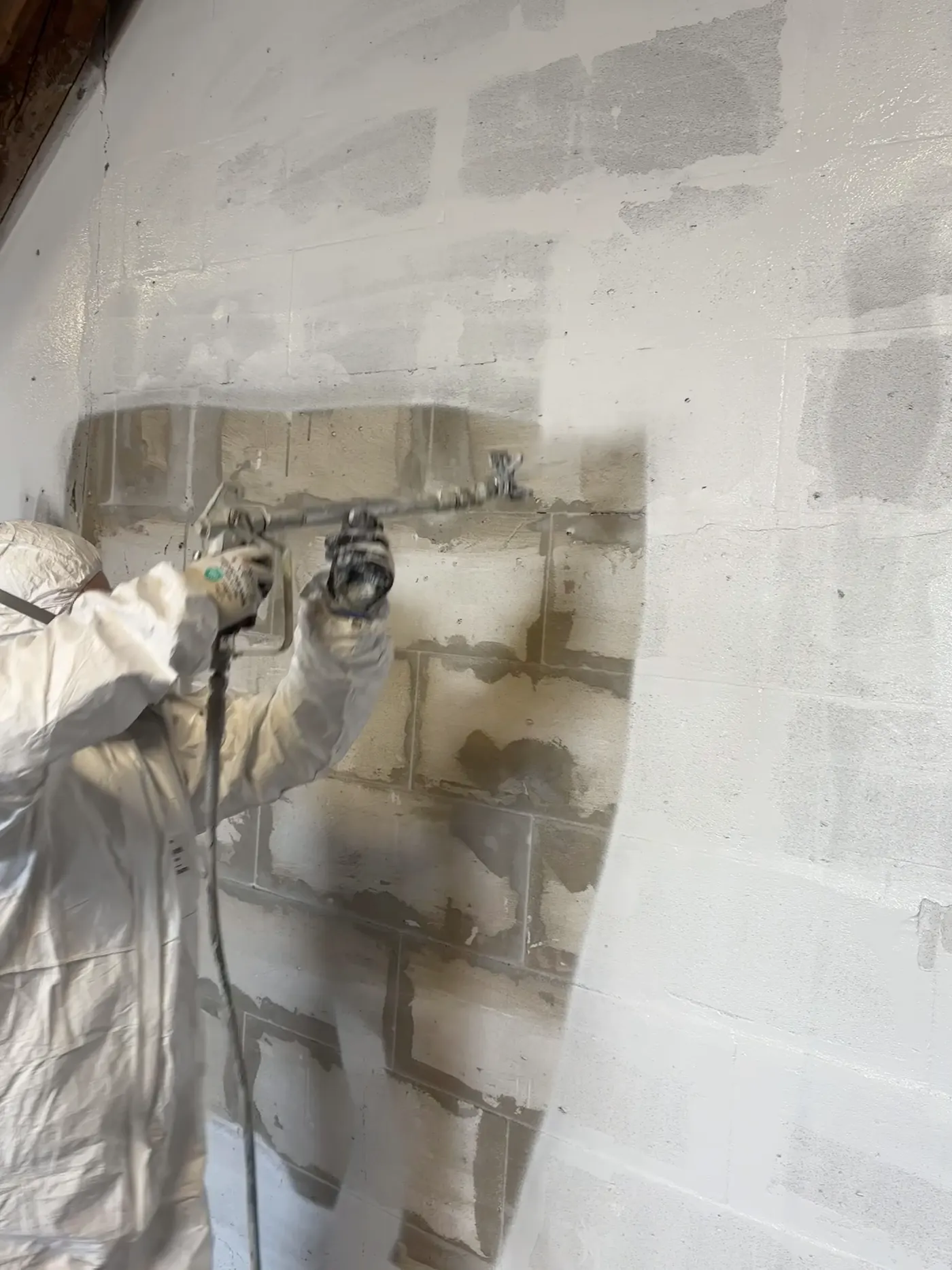 Airless-Arbeiten an einer alten Wand im Altbau, in einer Halle