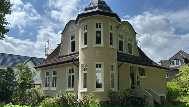 Fassade nach der mineralischen Gestaltung – warmes Cremeweiß mit abgesetzten Fensterrahmen