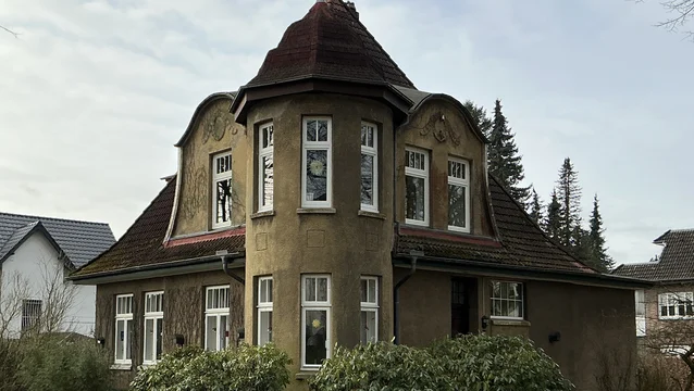 Dieselbe Fassade vor der Sanierung – stumpfer, verwitterter Altputz