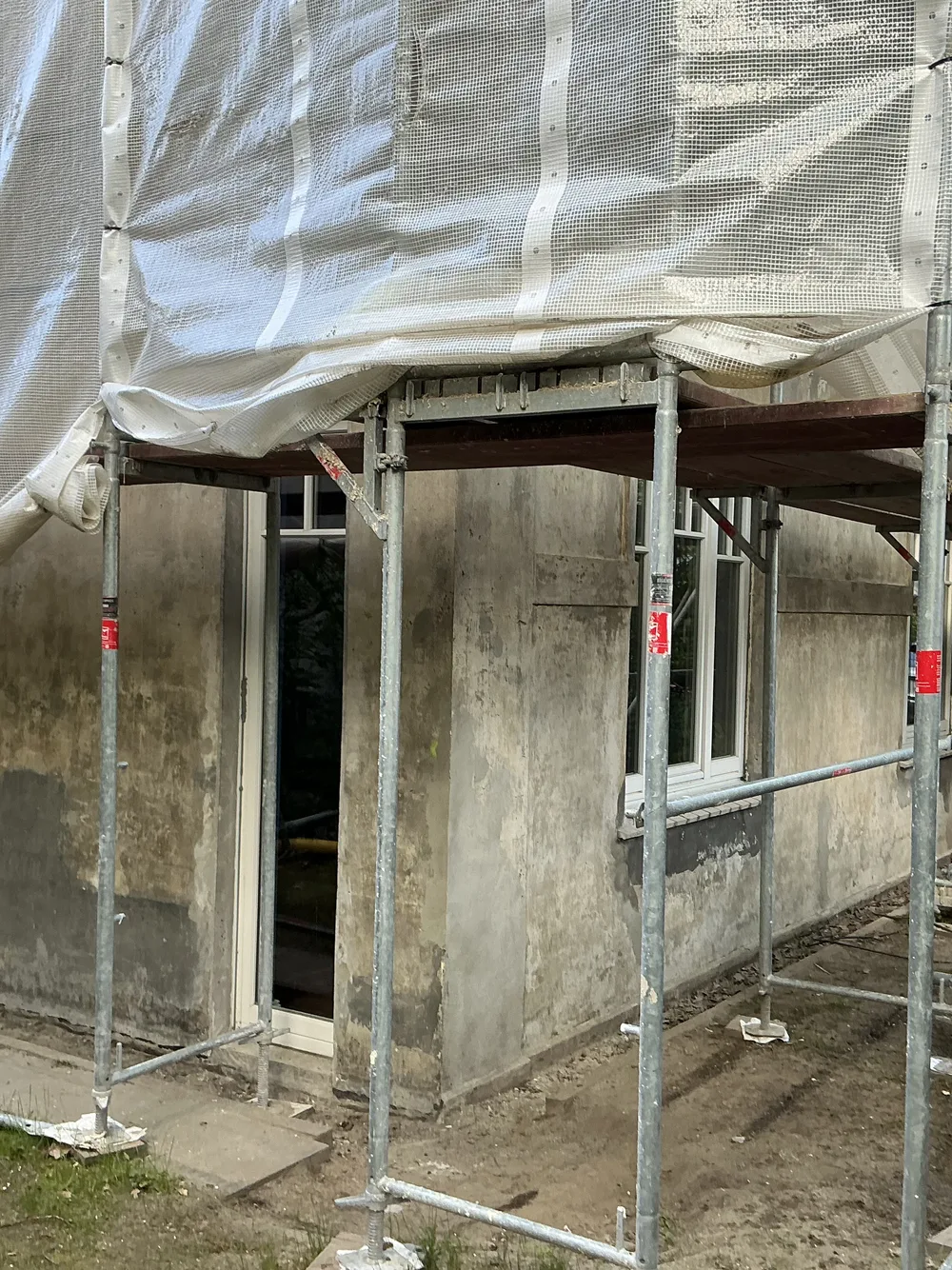 Vollständig eingerüstete Fassade mit Schutznetz vor der Sanierung