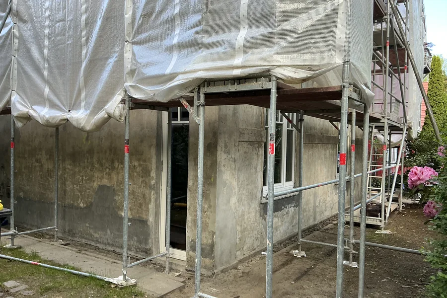Die eingerüstete Fassade vor der Sanierung, verwitterter Altputz